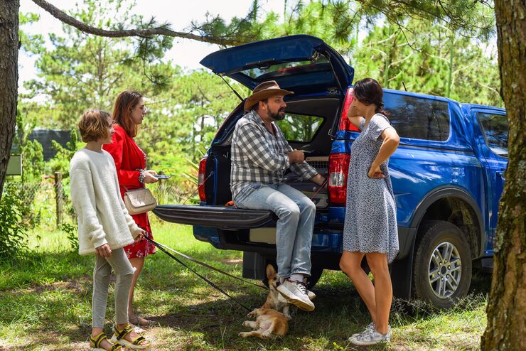 Family gathering near blue pickup truck.